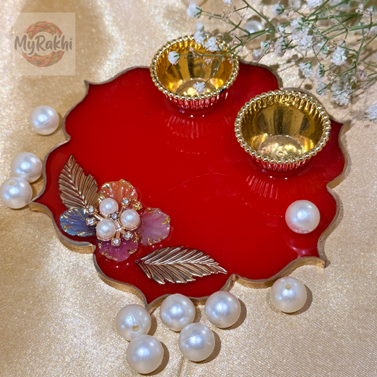 A lightweight, vibrant red resin thali with a scalloped gold border, adorned with delicate floral motifs and pearls, perfect for festive rituals.