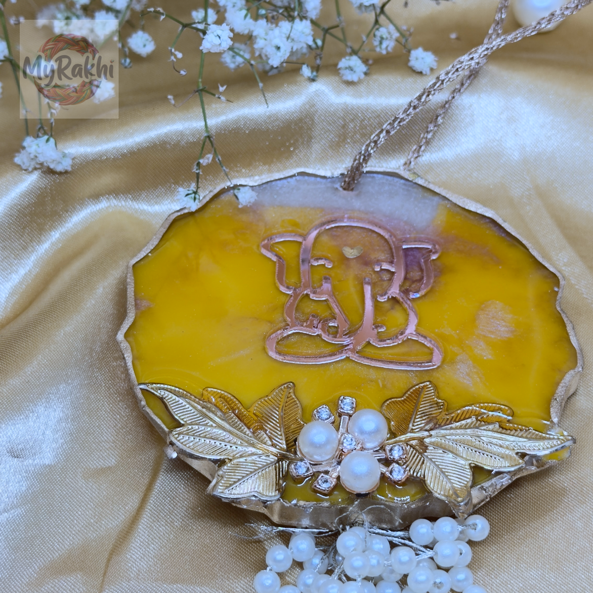 A beautifully crafted yellow resin hanging ornament featuring a golden Lord Ganesh motif, pearl clusters, and metallic leaf details for auspicious home decor.